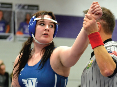 referree raises hand of female athlete after winning competition